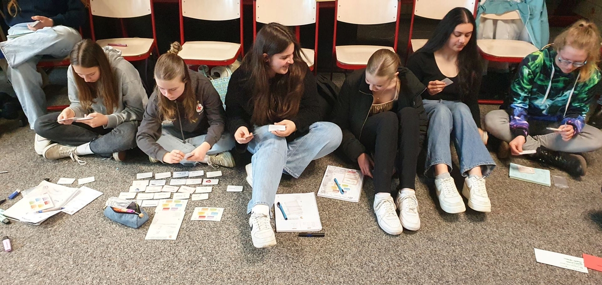 Mädchengruppe mit Karten vor sich auf dem Boden sitzend
